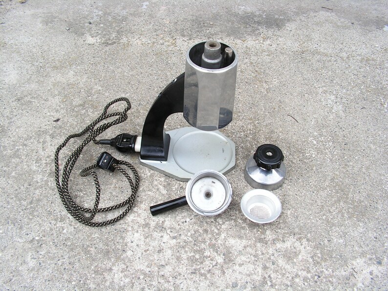 May include: A vintage silver and black electric coffee maker with a cord and a separate filter basket. The coffee maker has a round base and a tall, cylindrical top.