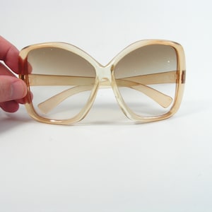 Puede incluir: Un par de gafas de sol grandes, de plástico marrón, con forma cuadrada.