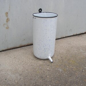 May include: White enamelware bucket with a black rim and a spout. The bucket has a speckled pattern.