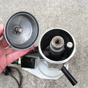 May include: A silver and black coffee maker with a removable lid and a handle. The coffee maker is disassembled, showing the inner workings.