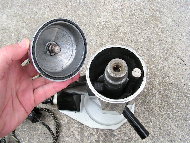 May include: A silver and black coffee maker with a removable lid and a handle. The coffee maker is disassembled, showing the inner workings.