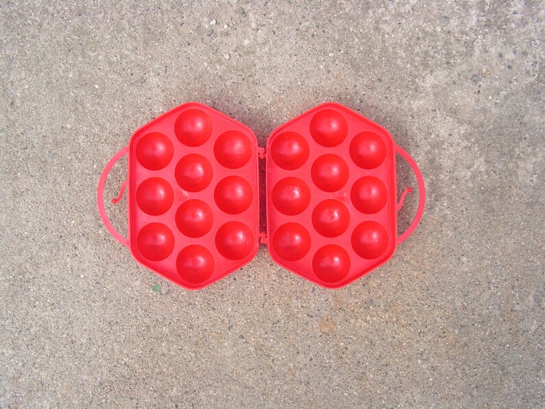 May include: A red plastic egg carton with 18 compartments, open and ready to hold eggs.