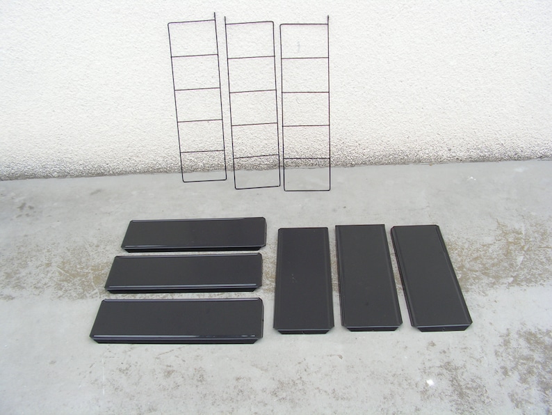 Puede incluir: Cinco estantes de metal negro con un marco de metal negro. Los estantes est&aacute;n vac&iacute;os y listos para ser utilizados para almacenamiento o exhibici&oacute;n.