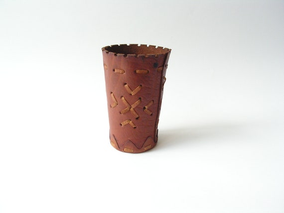 A hand-stitched vintage leather dice/shaker cup moonlighting as a pen holder — functional, tactile, and conversation-starting on any desk.