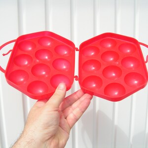 May include: Red plastic egg carton with 12 individual compartments for holding eggs.