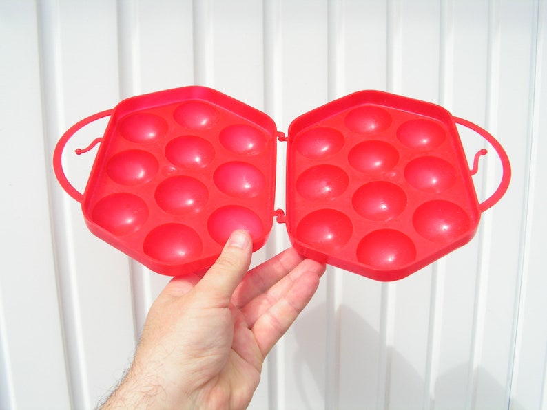 May include: Red plastic egg carton with 12 individual compartments for holding eggs.