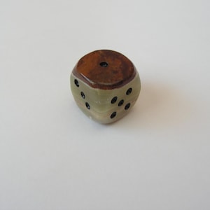 May include: A handcrafted dice with a unique design. The top and one side are a rich brown color, while the other sides are a light green with black dots. This decorative dice is perfect for game enthusiasts.