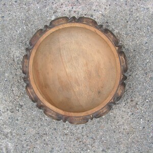 May include: A wooden bowl with a carved rim. The bowl is light brown and has a smooth, natural finish.