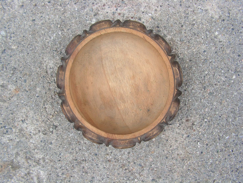 May include: A wooden bowl with a carved rim. The bowl is light brown and has a smooth, natural finish.