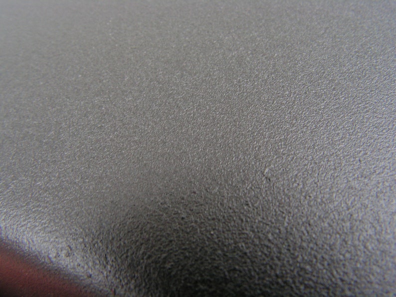 Puede incluir: Primer plano de una superficie texturizada gris oscuro.
