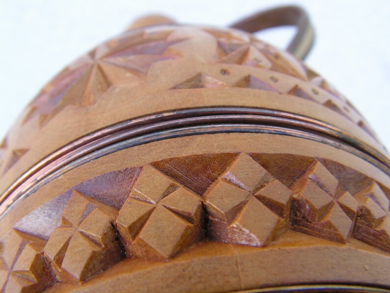 K&ouml;nnte beinhalten: Ein Holzbeh&auml;lter mit einem geschnitzten Design und einem Kupferband um die Oberseite. Der Beh&auml;lter hat einen Griff und ist aus hellem braunem Holz gefertigt.