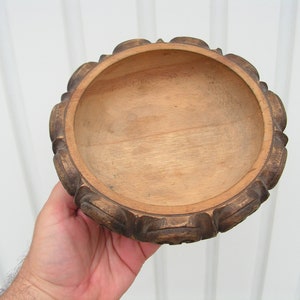 May include: A wooden bowl with a carved, dark brown rim and a smooth, light brown interior.