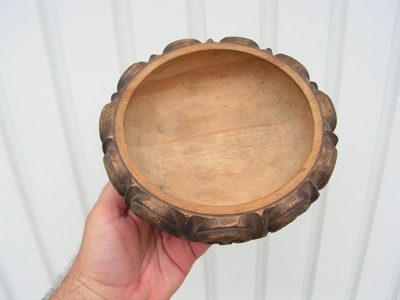 May include: A wooden bowl with a carved, dark brown rim and a smooth, light brown interior.
