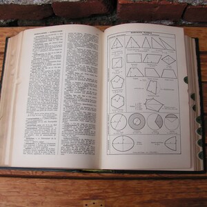 May include: An open vintage book with pages displaying text and geometric diagrams. The book is bound in a dark cover and rests on a wooden surface. The pages are aged with a yellowed hue, and the diagrams are in black ink.