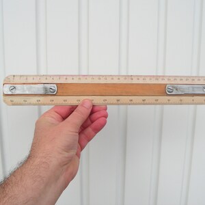 May include: A wooden ruler with metal accents and markings in inches. The ruler is 30 inches long.