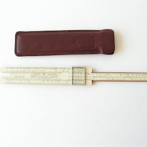 Może przedstawiać: Biała suwmiarka z brązowym skórzanym etui. Na suwmiarce widnieje napis "FABPИKA CЧETHbIX ПPИБOPOB".