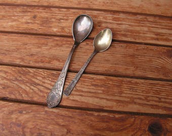 Può includere: Due cucchiai d'argento con manici decorati su una superficie di legno.