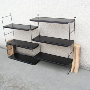 Puede incluir: Una estanter&iacute;a de pared de metal negro con cuatro estantes. Los estantes est&aacute;n hechos de metal negro y tienen un dise&ntilde;o simple y moderno.