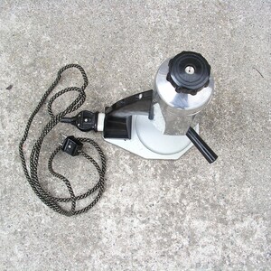 May include: A silver and black electric coffee maker with a black cord and plug. The coffee maker has a round, silver base and a black handle.