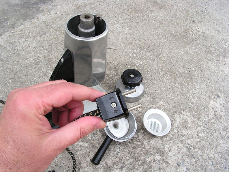 May include: A silver and black electric coffee maker with a detachable cord and plug. The coffee maker is disassembled, showing the internal components.