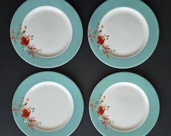 Puede incluir: Un juego de cuatro platos redondos de cerámica, cada uno con un centro blanco sólido y un borde ancho de color verde azulado. Un delicado estampado floral en tonos rojo, naranja y azul claro está impreso en el lado izquierdo de cada plato.