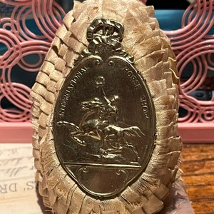 Vintage cream English uk equestrian horse ribbon prize altered arts show award early 1900s gold toned face tin international horse show