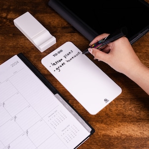 May include: A white dry-erase board with a black marker and the text "TO-DO • lesson plans • grade homework" written on it.