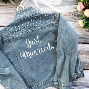 May include: A light blue denim jacket with pearl embellishments on the back. The jacket has the text "Just Married" and the date "20.04.2024" embroidered on the back.