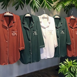 May include: A set of three ceramic mugs with a speckled, cream-colored glaze. Each mug features a different hand-painted floral design in shades of blue, green, and yellow. The mugs have a simple, rounded shape and a comfortable handle.