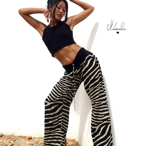 May include: A woman wearing a black crop top and zebra print trousers poses against a white wall. The text "Malamakka..." is visible in the top right corner of the image.