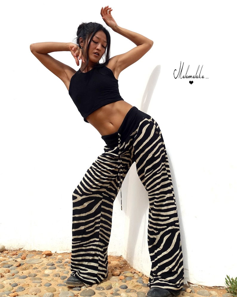 May include: A woman wearing a black crop top and zebra print trousers poses against a white wall. The text "Malamakka..." is visible in the top right corner of the image.