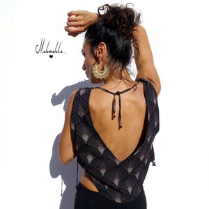 Puede incluir: Top negro y beige estampado con espalda baja y cierre de lazo. El top presenta un diseño en forma de abanico. La imagen también incluye pendientes dorados y el texto "Mahalakka..."