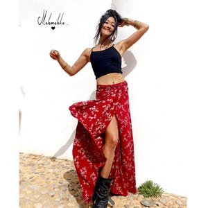 Puede incluir: Una falda envolvente roja con estampado floral blanco y abertura alta. Se combina con un top corto negro y botas negras. La imagen incluye el texto "Mahamakka.." en cursiva.