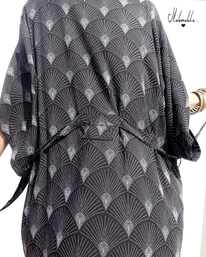 May include: Black kimono-style robe with a white fan-shaped pattern. The robe has a tie belt and wide sleeves. The text "Mahamalaka..." is visible in the upper right corner. The robe is made of a soft, flowing fabric.