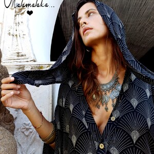 May include: A black and white patterned hooded top with a V-neck. The top has a fan-like design and is buttoned. The image also includes the text "Malamalaka..." in cursive.
