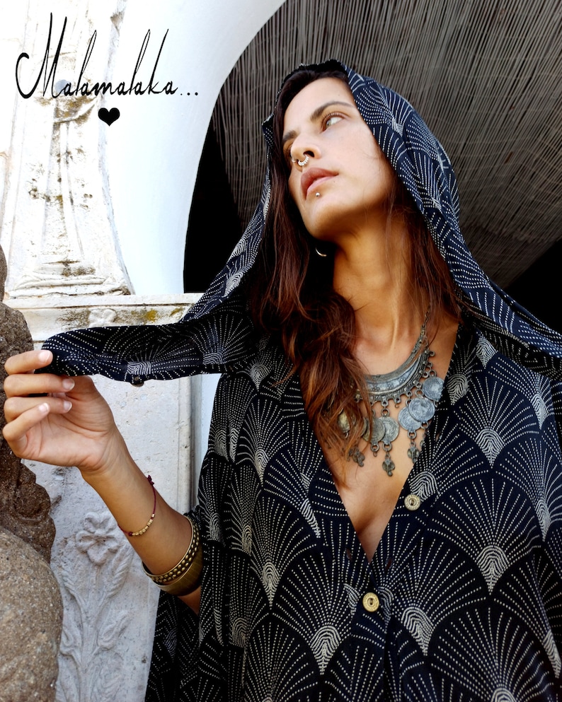 May include: A black and white patterned hooded top with a V-neck. The top has a fan-like design and is buttoned. The image also includes the text "Malamalaka..." in cursive.
