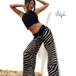 May include: A woman wearing a black crop top and zebra print trousers poses against a white wall. The text "Malamakka..." is visible in the top right corner of the image.