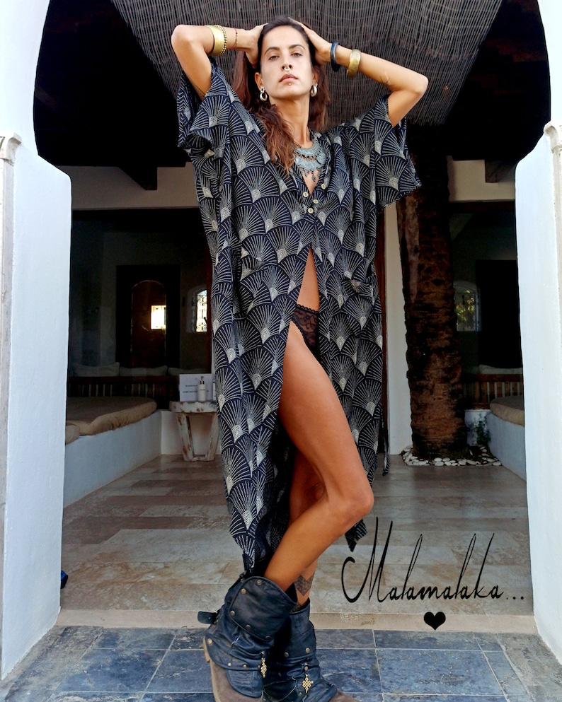 May include: A black and gold patterned kimono-style robe with a button-down front. The robe features a fan-like design. The model is wearing black boots. The word "Malamalaka" is written in cursive.