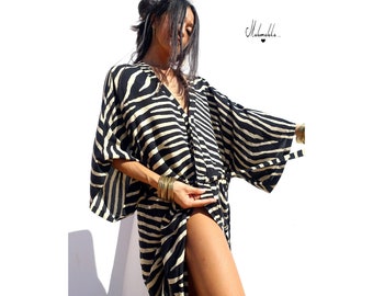 May include: A black and white zebra print kimono with long sleeves and a tie belt. The kimono is made of a soft, flowing fabric.