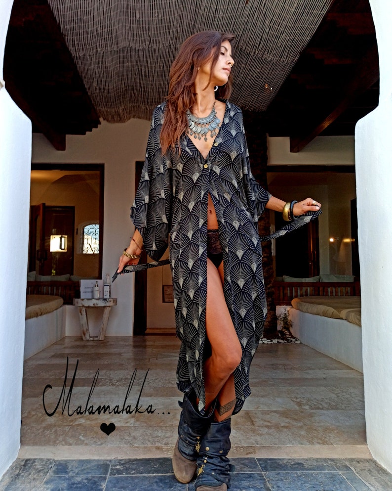 May include: A long, black and white patterned kimono-style dress with a button-down front. The dress features a fan-like design and is paired with black boots. The word "Malamalaka..." is written in cursive on the bottom left.