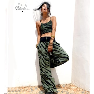 Puede incluir: Conjunto de dos piezas con estampado de cebra en verde oliva y negro. El conjunto incluye un top corto y pantalones de pernera ancha. El top tiene tirantes finos y los pantalones una cintura negra. El conjunto se lleva con pulseras doradas. La imagen tiene el texto "Mahamala..." en la esquina superior izquierda.