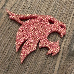 May include: A pink, sparkly, plastic animal head, possibly a panther or a lion, with a detailed design.
