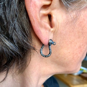 May include: A pair of black metal hoop earrings with a textured finish. The earrings are simple and understated, and would make a great addition to any jewelry collection.