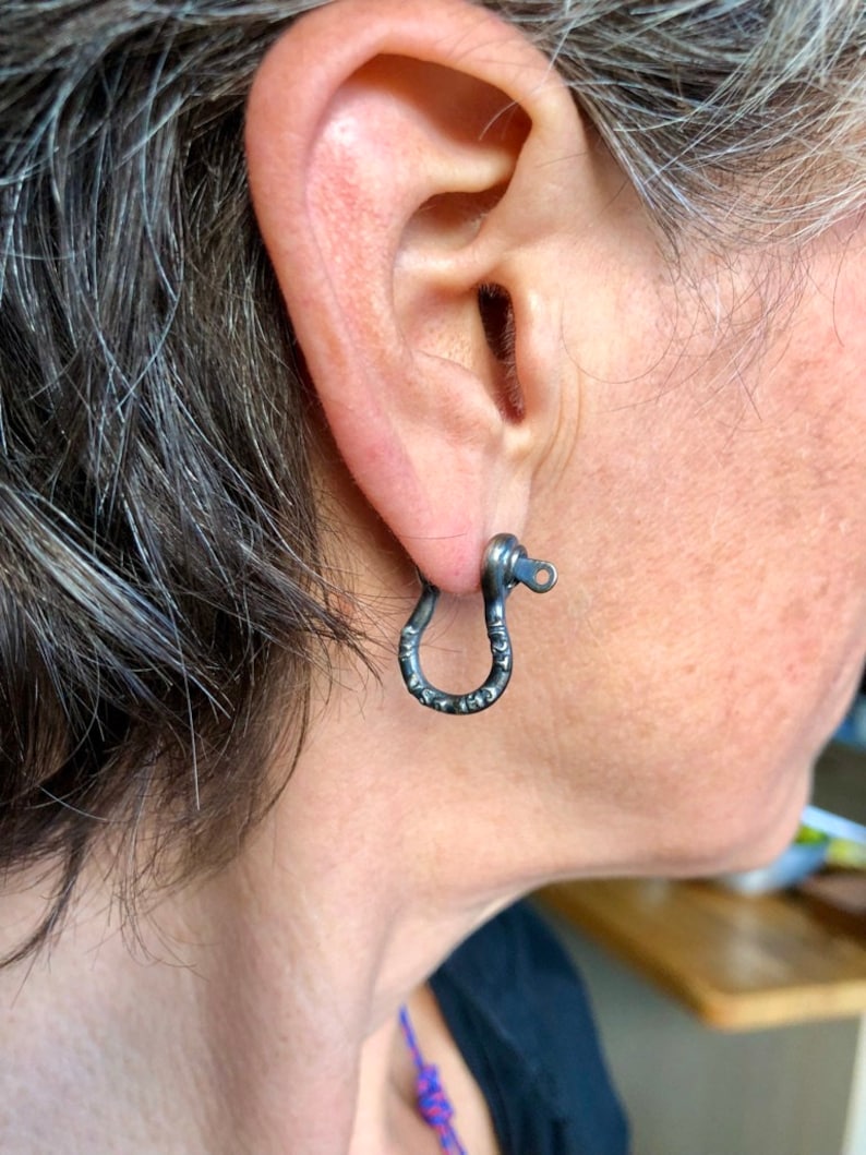 May include: A pair of black metal hoop earrings with a textured finish. The earrings are simple and understated, and would make a great addition to any jewelry collection.