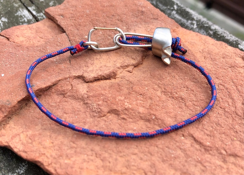 May include: A blue and red rope with a silver carabiner and a silver metal climbing device.