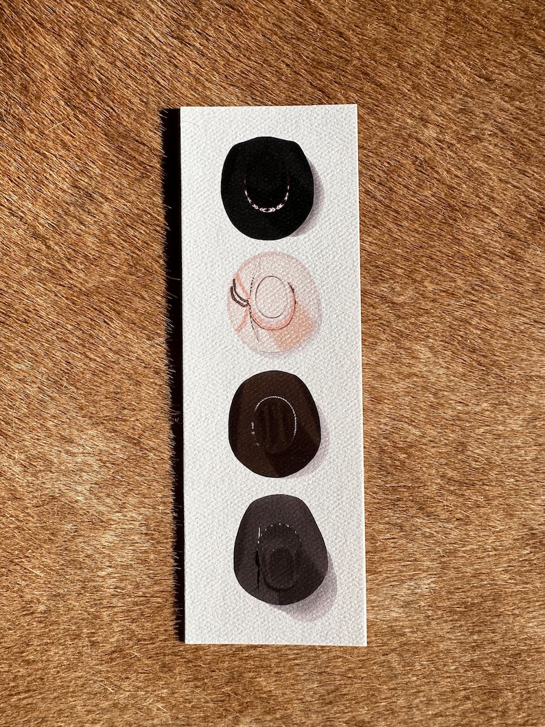 May include: Four different cowboy hats in a row on a white background. The hats are black, beige, brown, and gray.