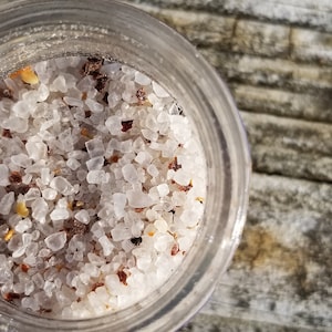 May include: Close-up of a glass jar filled with white sea salt and red pepper flakes.