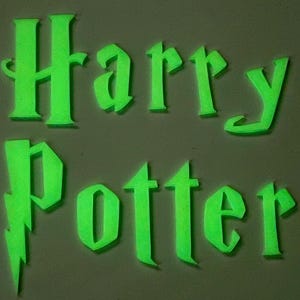 May include: Glow-in-the-dark green lettering spells out "Harry Potter" with a lightning bolt symbol. The letters are in a stylized font, and the image has a dark background. The overall theme is related to the popular fantasy book series.
