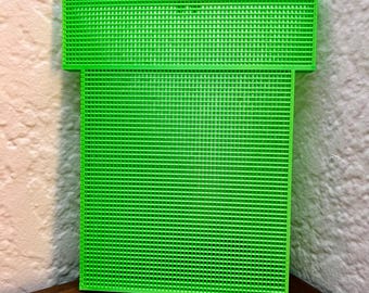 May include: A green plastic pipe-shaped object with a grid pattern. The object is made of a 3D printed material.