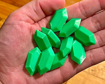 May include: A group of bright green, faceted, plastic gems in the shape of a hexagon. The gems are in a person's hand.